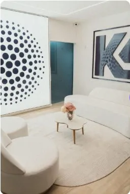 Sala de espera branca com sofá, mesa de centro e o logo KG na parede