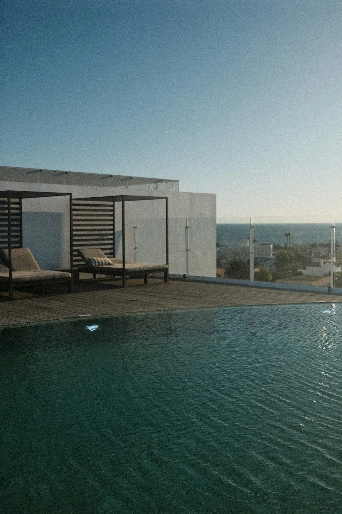Piscina na cobertura de um prédio com espreguiçadeiras e o mar ao fundo