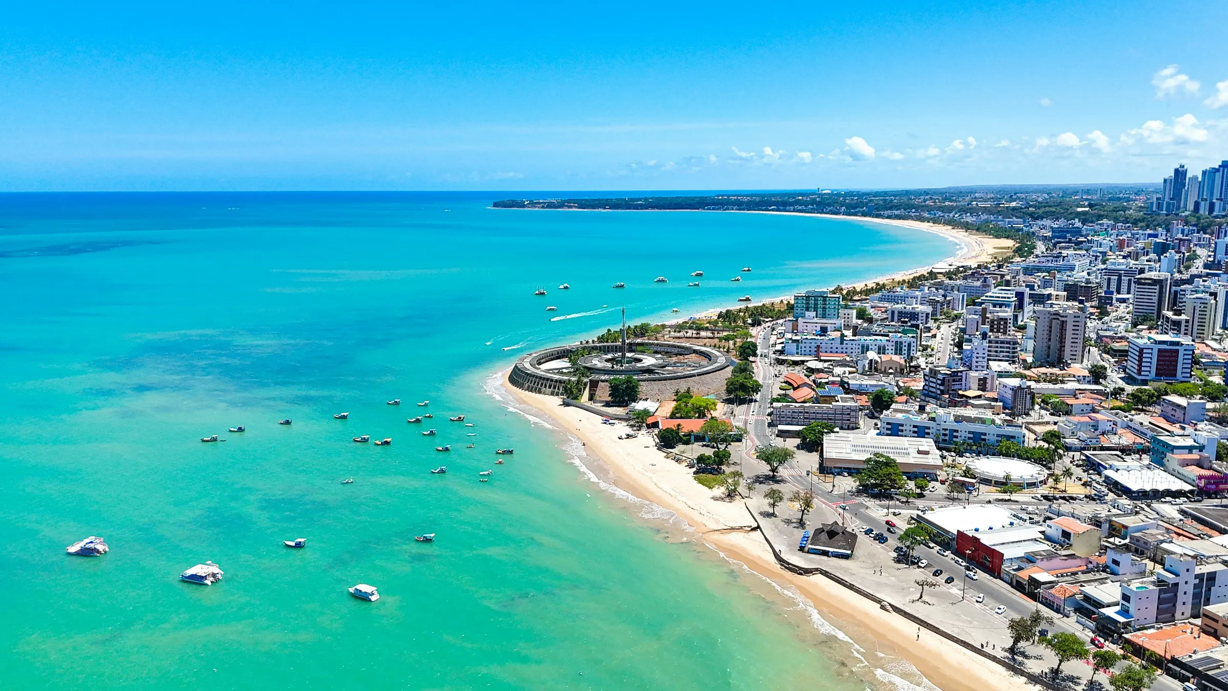 Vista aérea da orla de João Pessoa, com o mar azul-turquesa, a praia de Tambaú e os prédios da cidade