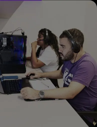 Dois integrantes da equipe trabalhando com fones de ouvido em frente aos computadores